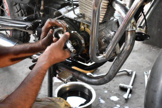 A mechanic is repairing motorbike in his motor garage, maintenance